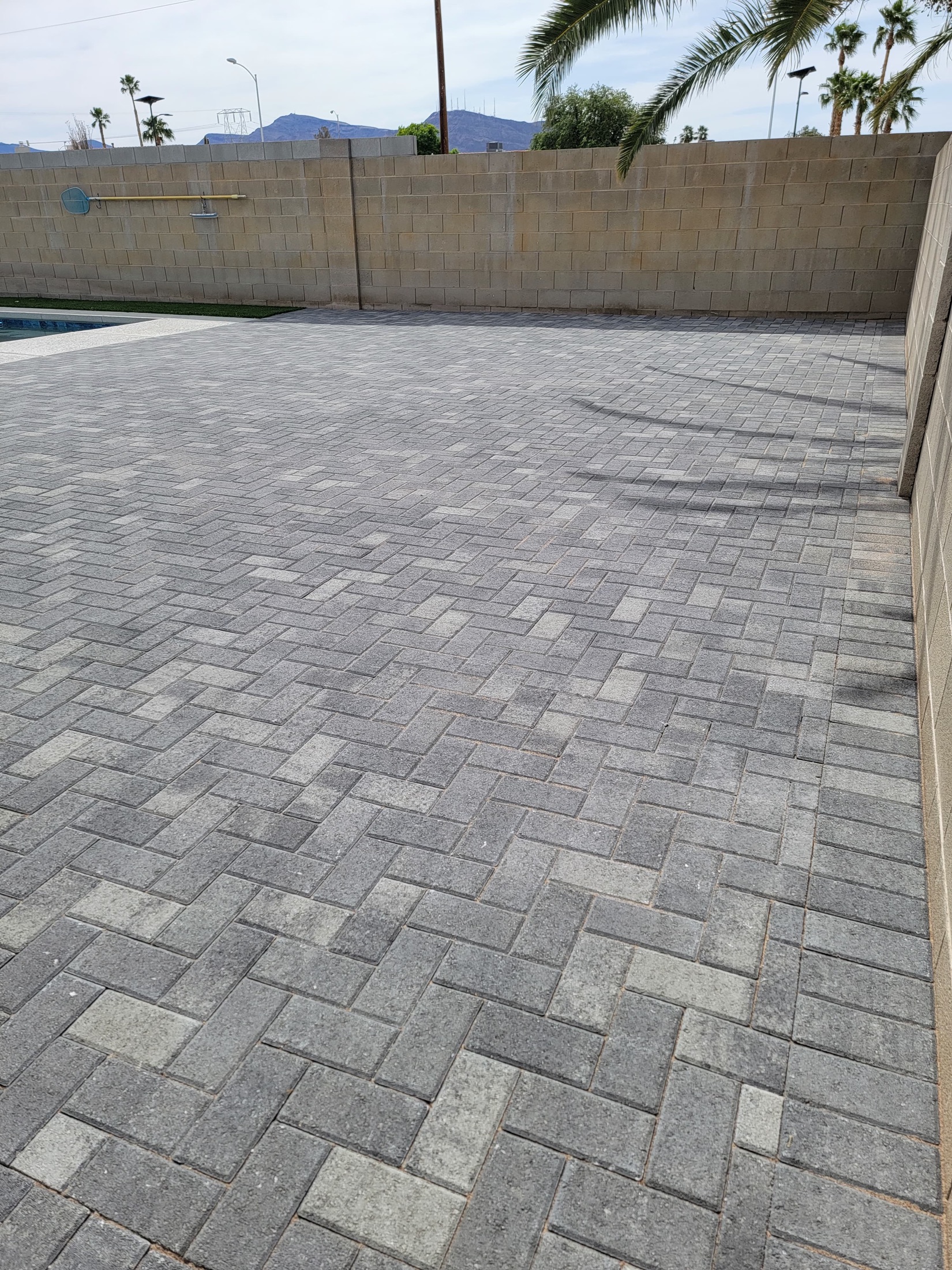 Finished gray paver patio surface with herringbone pattern and clean edges