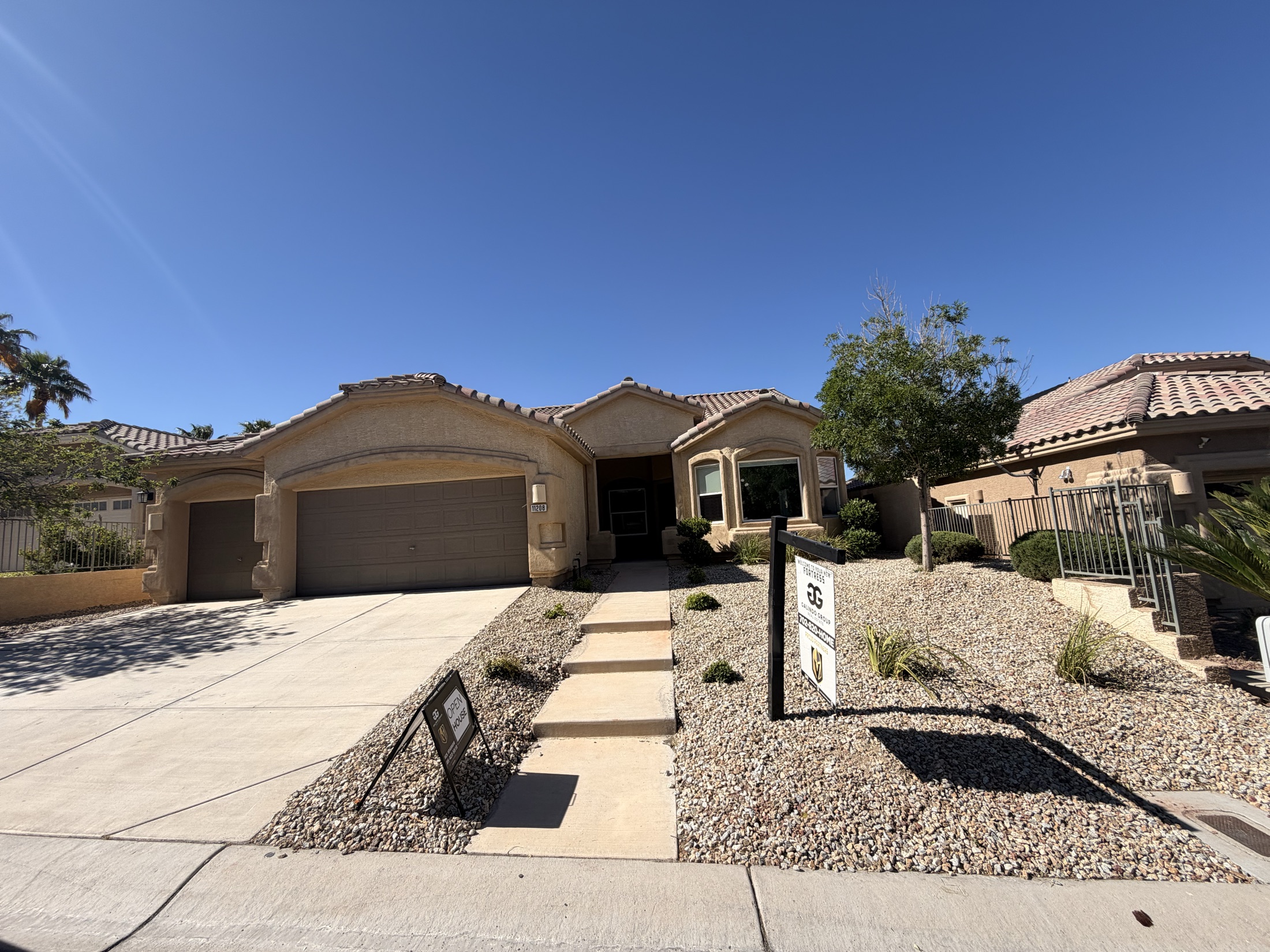 Low-water rock landscape around a white Las Vegas home with desert trees and palms
