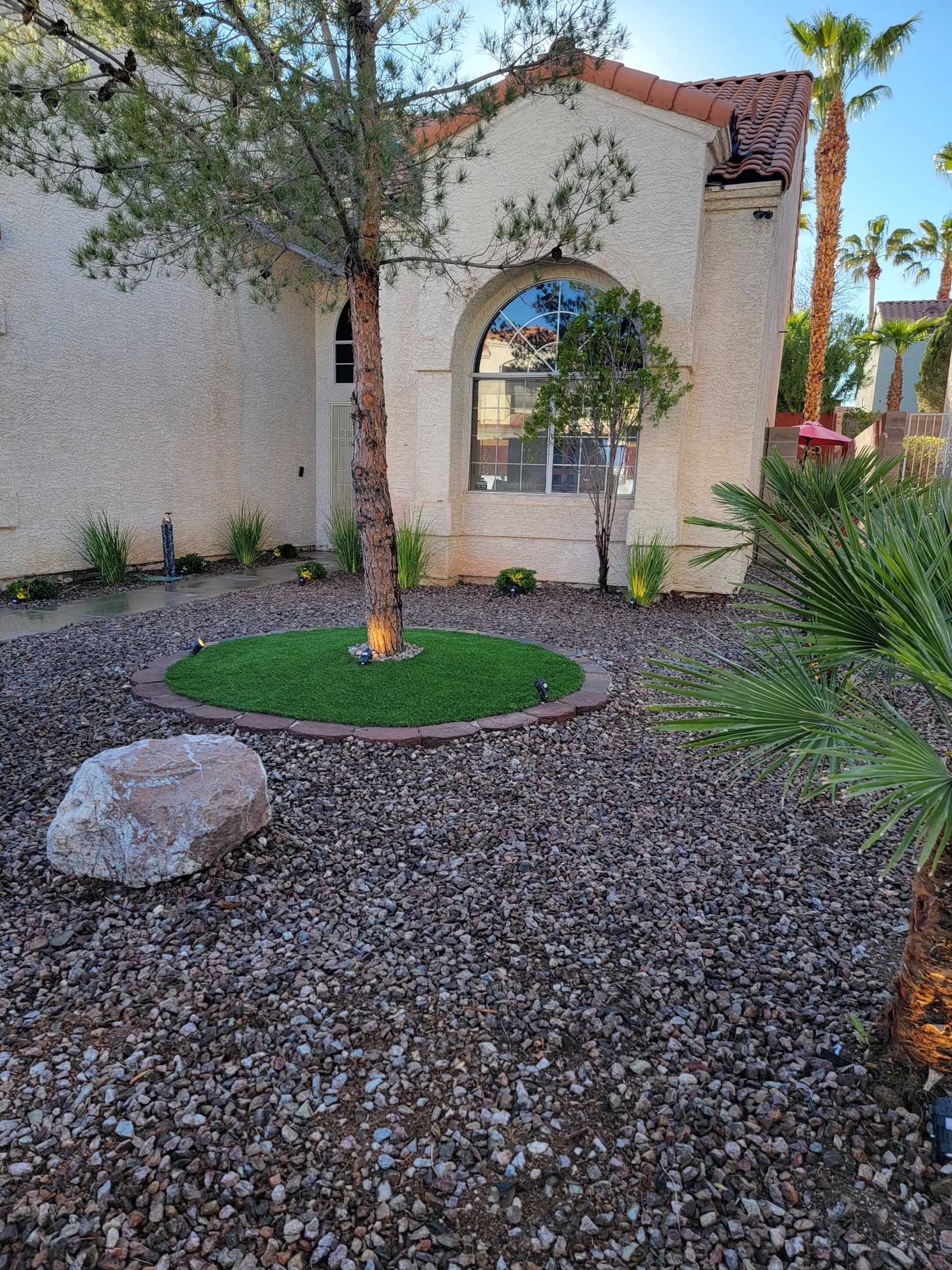 Front yard desert rock installation with boulders, yucca, and driveway border