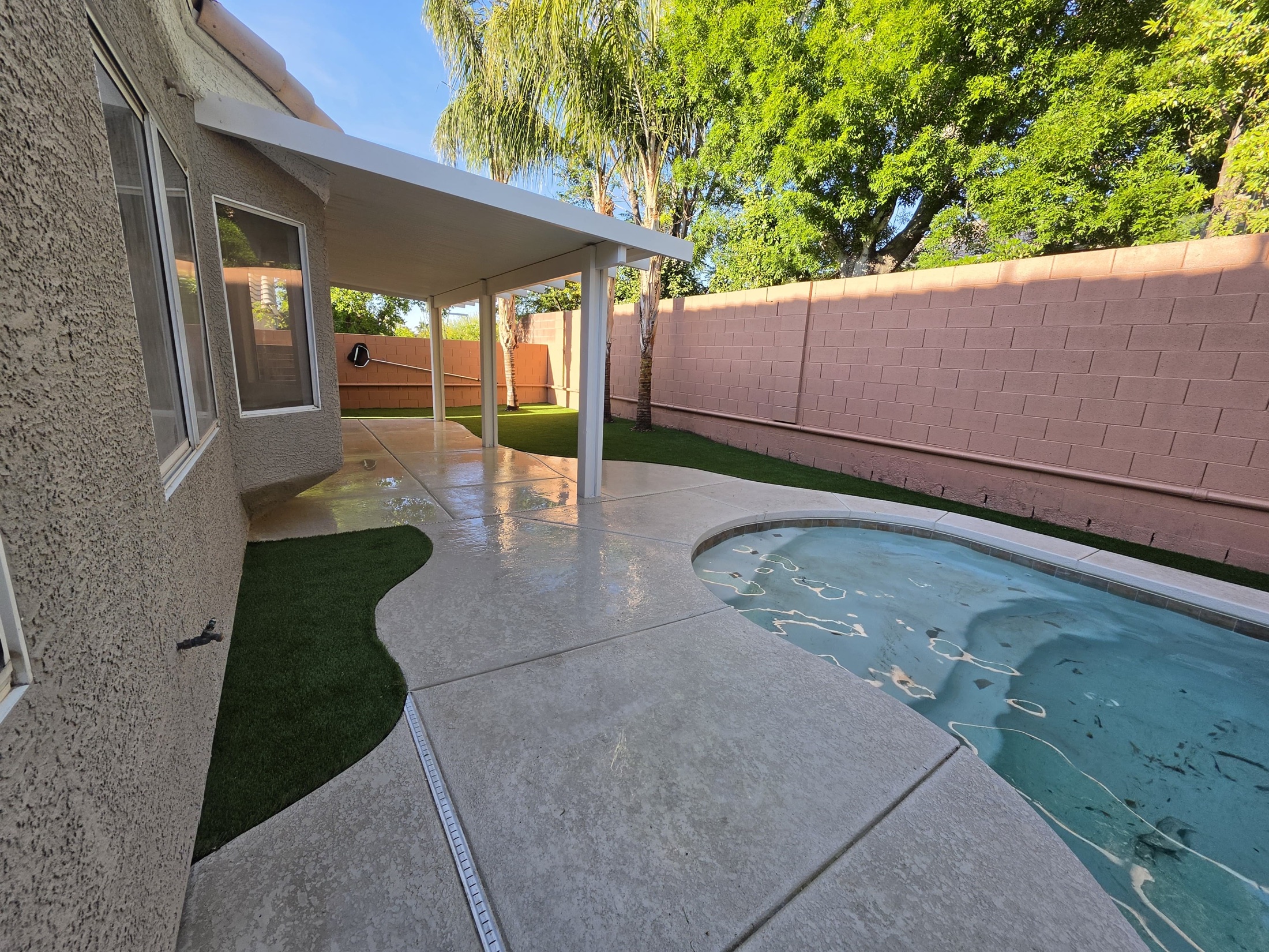 Artificial turf installed around pool deck and backyard patio
