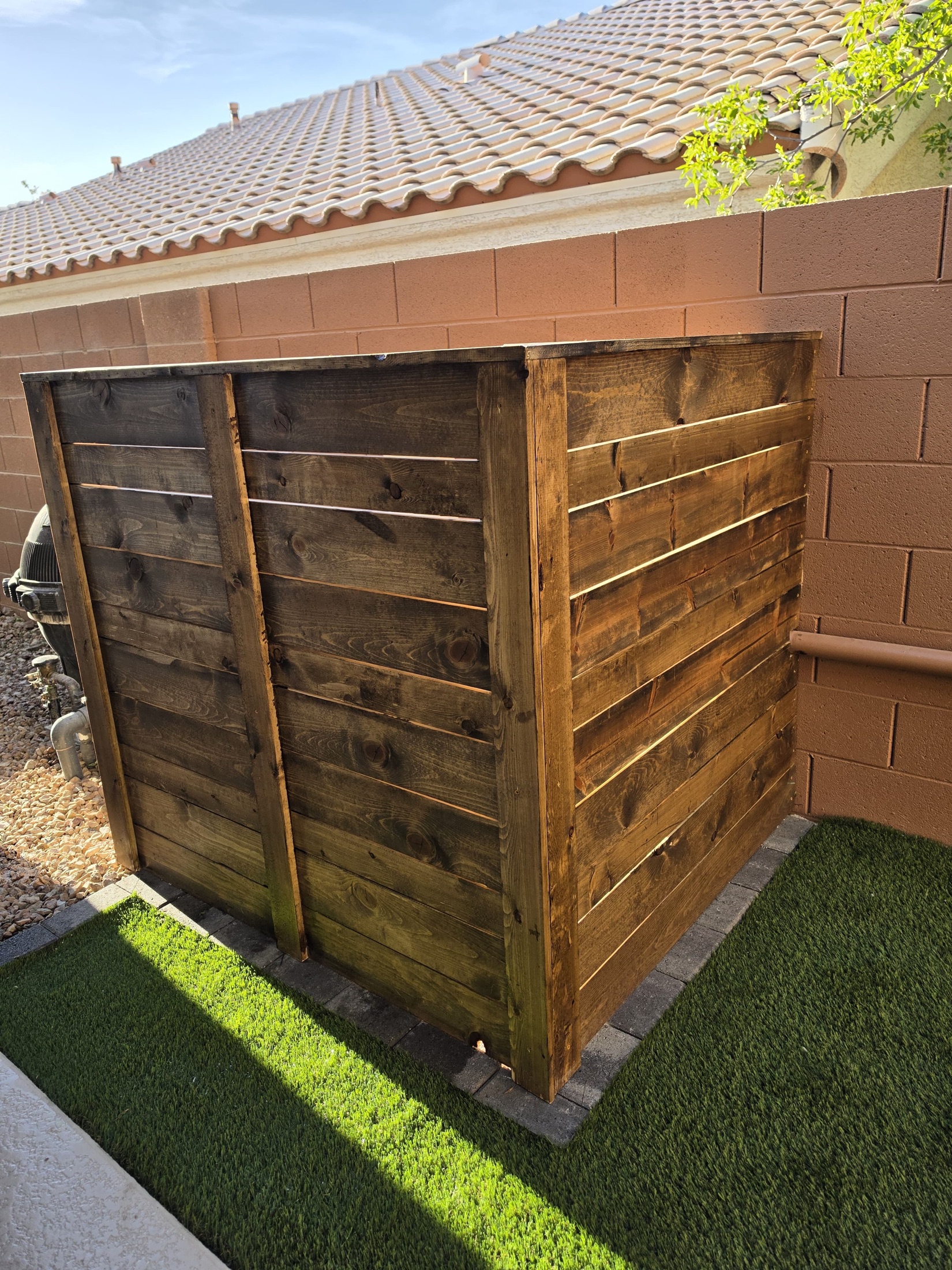 Artificial grass installed around a stained wood privacy screen