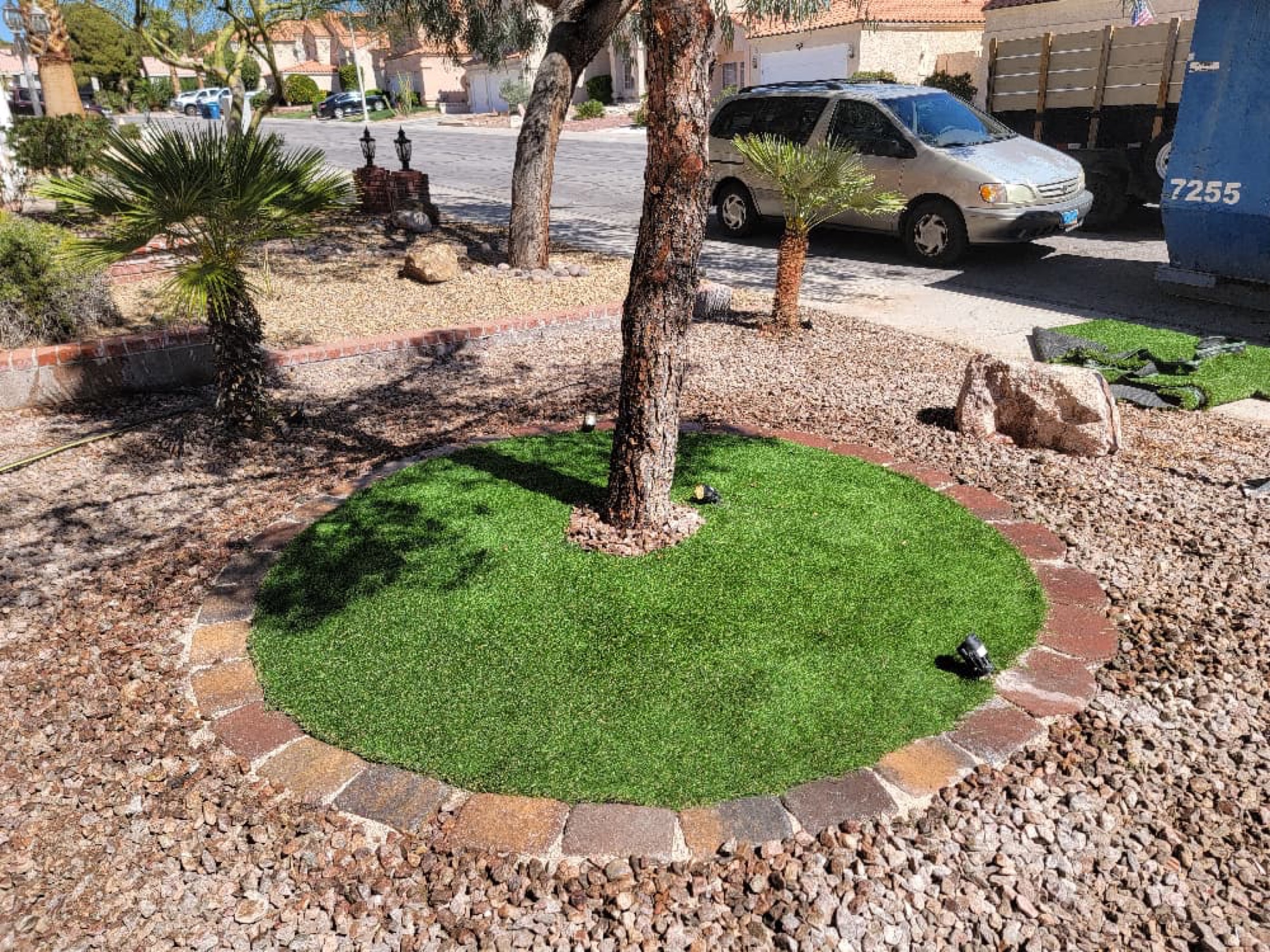 Small circular artificial turf area around a tree with paver border and desert rock