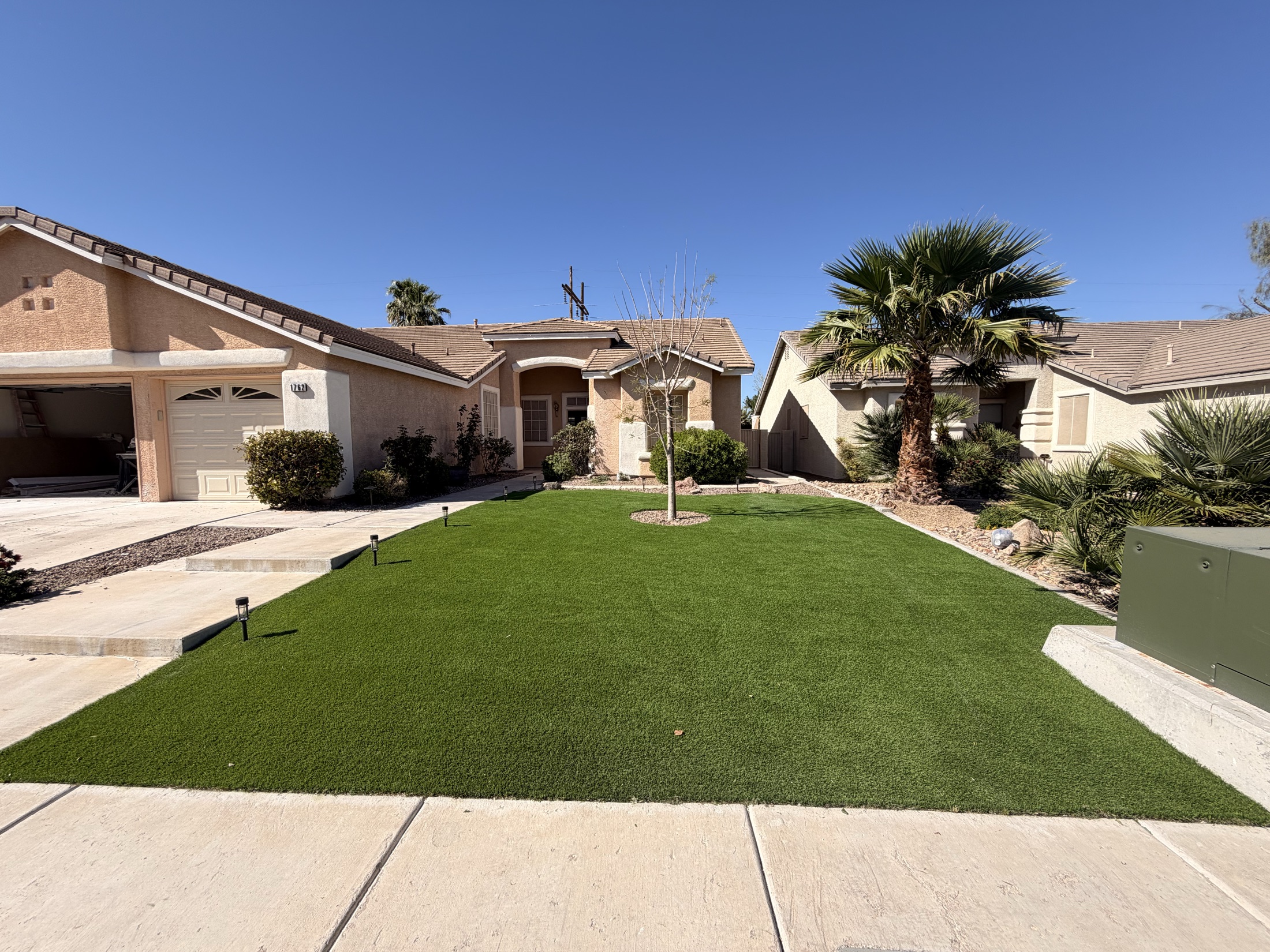 Artificial turf rectangle with paver border and decorative rock in a backyard